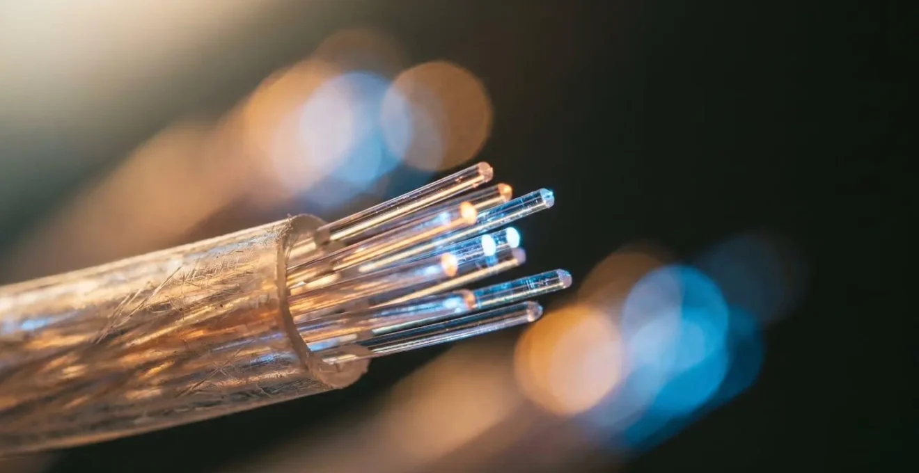 Close-up of illuminated fiber optic cables transmitting data streams with bokeh light particles representing high-bandwidth 4K streaming network