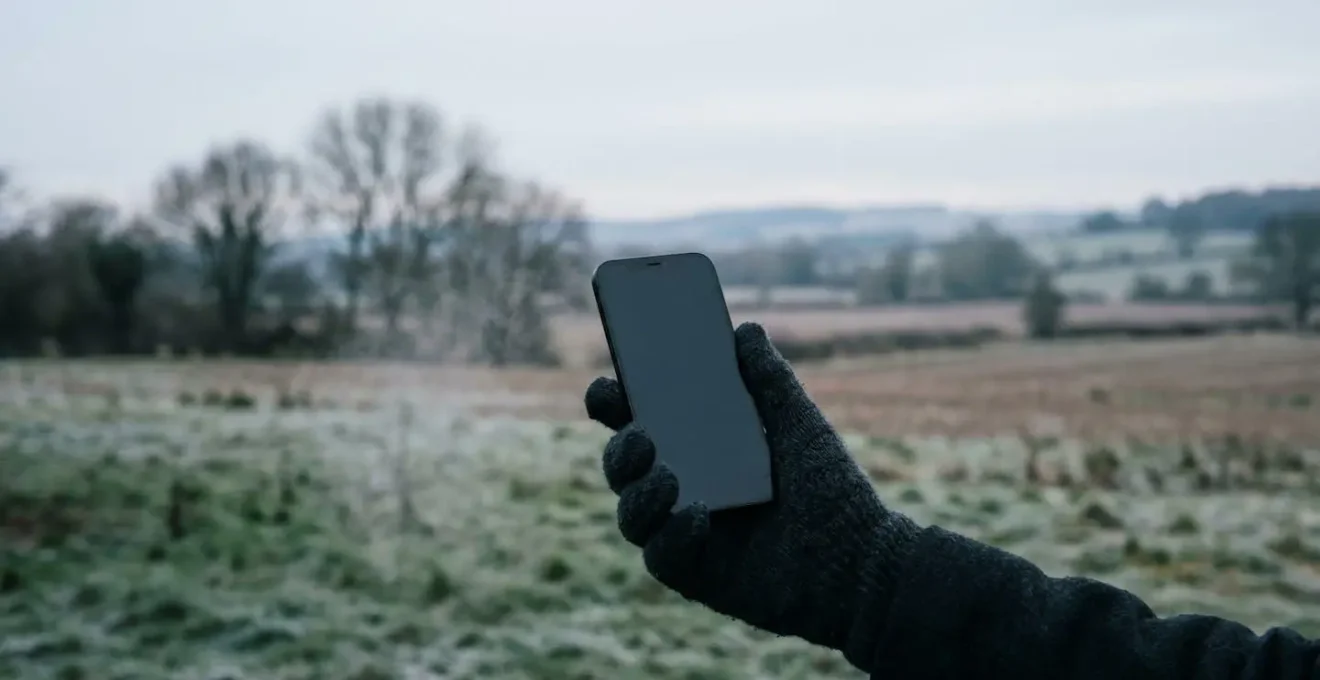 Smartphone screen displaying critical battery warning outdoors in freezing British winter conditions